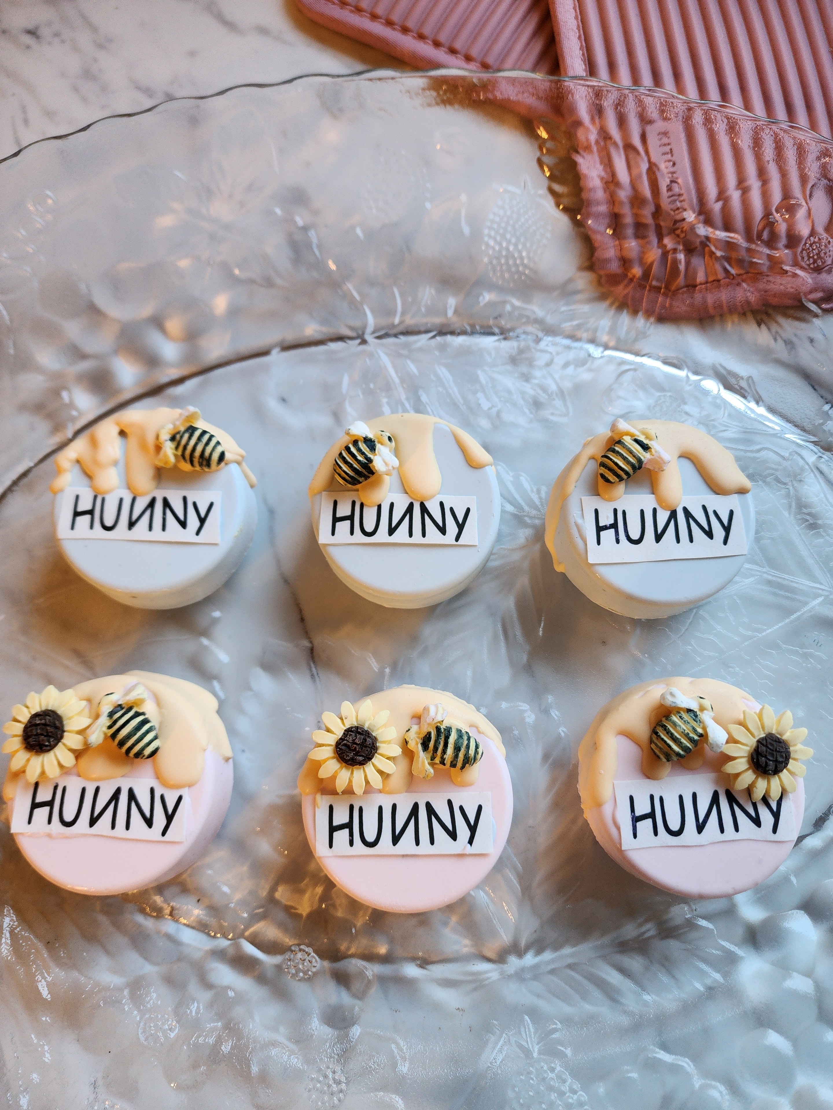 Decorated Hunny Oreo cookies with bee and sunflower designs on a glass tray